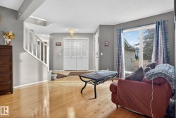 Spacious living area featuring light wood-finish flooring, a contemporary ceiling light fixture, and a large window - 