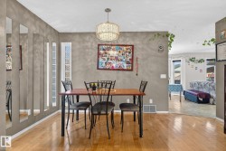 Dining area featuring wood-finish flooring and a contemporary chandelier - 