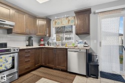 Kitchen featuring wood cabinetry, white subway tile backsplash, light-toned stone-finish countertops, stainless steel appliances, and a sliding glass door to the exterior - 