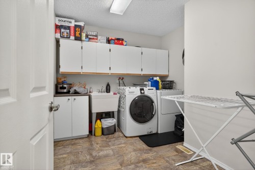 Dedicated utility room featuring white cabinetry and wood-finish countertops - 3912 31 Street, Edmonton, AB 