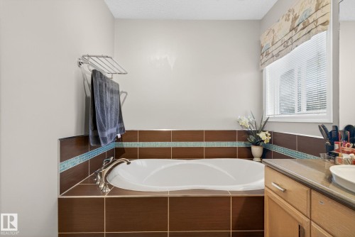 Soaking tub with bronze-toned tile surround and accent trim, featuring brushed nickel fixtures - 3912 31 Street, Edmonton, AB 