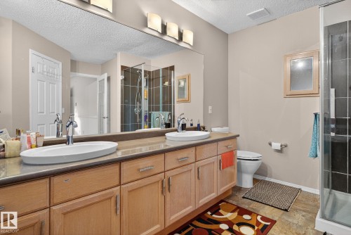 Double vanity with wood-finish cabinetry, dual vessel sinks, and an expansive mirror - 3912 31 Street, Edmonton, AB 