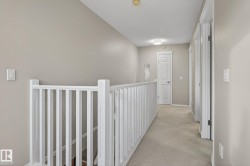 Upper level hallway featuring light gray wall paint and light neutral carpeting - 