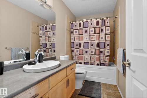 Bathroom featuring a vanity with a white vessel sink, wood-finish cabinetry, and a large mirror - 3912 31 Street, Edmonton, AB 