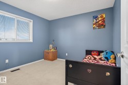 Bedroom featuring light blue walls, neutral carpet flooring, and a white-framed window with blinds - 