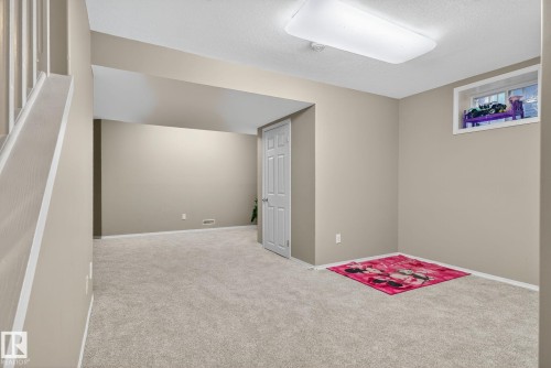 Spacious room featuring neutral paint, light gray carpeting, white trim, a flush-mount ceiling light, and a white interior door - 3912 31 Street, Edmonton, AB 