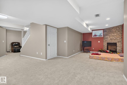 Spacious finished basement featuring light-toned carpeting and a corner fireplace with a stone surround - 3912 31 Street, Edmonton, AB 