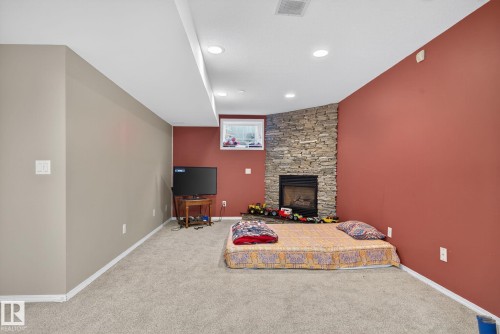 Carpeted interior space featuring a corner fireplace with a stacked stone surround, recessed lighting, and a drop ceiling with integrated lighting - 3912 31 Street, Edmonton, AB 