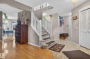 Inviting foyer featuring tile flooring, a carpeted staircase with white railings, and an adjacent room with wood-finish flooring - 3912 31 Street, Edmonton, AB 