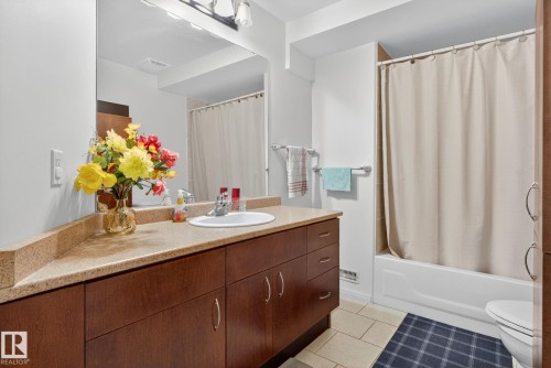 Bathroom featuring a dark wood-finish vanity with a light speckled countertop, an integrated sink, and a wall-mounted mirror - 3912 31 Street, Edmonton, AB 