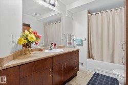 Bathroom featuring a dark wood-finish vanity with a light speckled countertop, an integrated sink, and a wall-mounted mirror - 
