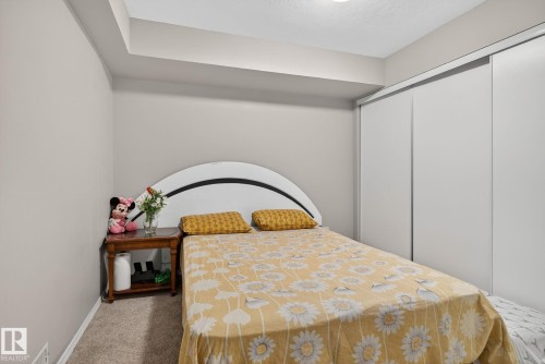 Bedroom featuring neutral wall paint, carpet flooring, a built-in closet with sliding doors, and a ceiling-mounted light fixture - 3912 31 Street, Edmonton, AB 
