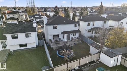 Rear exterior featuring a spacious wooden deck with a sliding glass door entry, a large green space, and two storage sheds - 3912 31 Street, Edmonton, AB 