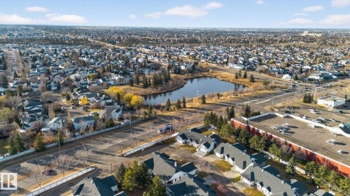 Expansive suburban area featuring a central pond, established residential properties, mature trees, commercial structures, and paved roadways - 3912 31 Street, Edmonton, AB 