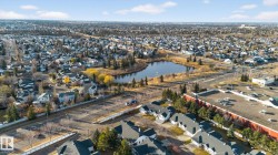 Expansive suburban area featuring a central pond, established residential properties, mature trees, commercial structures, and paved roadways - 