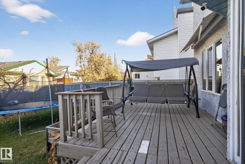 Wood-decked patio featuring a slatted railing, lattice skirting, and an exterior with textured stucco siding - 3912 31 Street, Edmonton, AB 