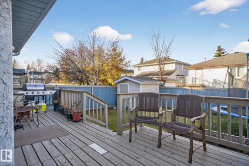 Spacious outdoor deck with a wooden railing and stairs, featuring a light blue privacy fence and a detached storage shed - 3912 31 Street, Edmonton, AB 