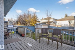 Spacious outdoor deck with a wooden railing and stairs, featuring a light blue privacy fence and a detached storage shed - 