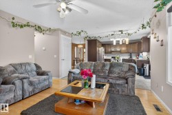 Open-concept living area featuring wood-finish flooring and a ceiling fan with integrated lighting - 