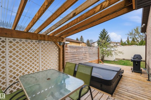 Wood-deck patio featuring a hot tub, a lattice privacy screen, and a pergola with a translucent roof - 18648 57 Avenue, Edmonton, AB - Outdoor With Deck Patio Veranda With Exterior