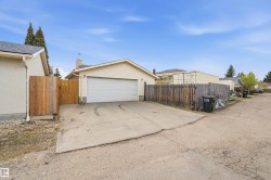 Detached garage with a single overhead door, concrete driveway, and wood fencing - 
