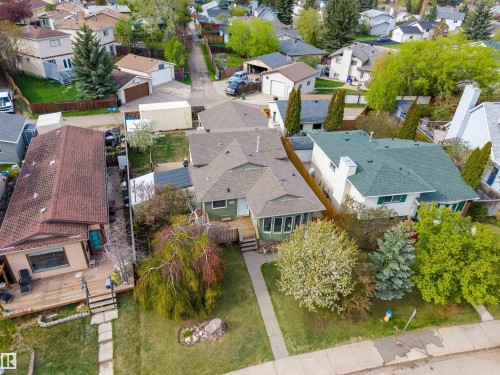 Residential property featuring a green-sided exterior, a pitched roof, and a front yard with mature trees - 18648 57 Avenue, Edmonton, AB - Outdoor With View