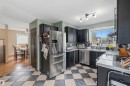 Kitchen featuring black cabinetry, stainless steel appliances, and checkerboard floor tiling - 18648 57 Avenue, Edmonton, AB  - Indoor Photo Showing Kitchen With Double Sink 