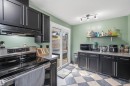 Kitchen featuring dark cabinetry, speckled countertops, stainless steel range, track lighting, and checkerboard flooring - 18648 57 Avenue, Edmonton, AB  - Indoor Photo Showing Kitchen 