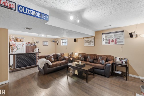 Spacious entertainment area featuring wood-finish flooring, recessed lighting, and a built-in bar with a textured panel - 18648 57 Avenue, Edmonton, AB - Indoor