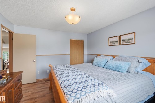 Bedroom featuring wood-finish flooring, two-tone wall treatment, and a semi-flush mount ceiling light fixture - 18648 57 Avenue, Edmonton, AB - Indoor Photo Showing Bedroom