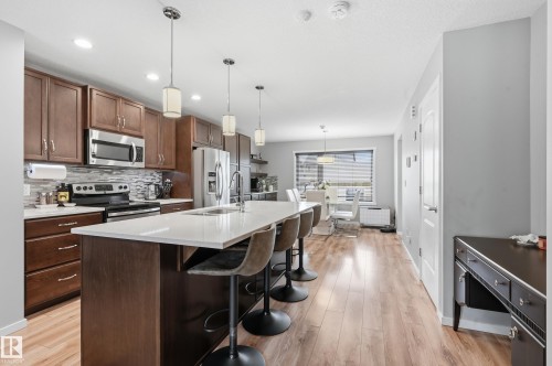 Open-concept kitchen featuring an oversized island with seating, stainless steel appliances, wood-finish cabinetry, a tiled backsplash, and recessed and pendant lighting - 3457 Cutler Crescent, Edmonton, AB - Indoor Photo Showing Kitchen With Upgraded Kitchen