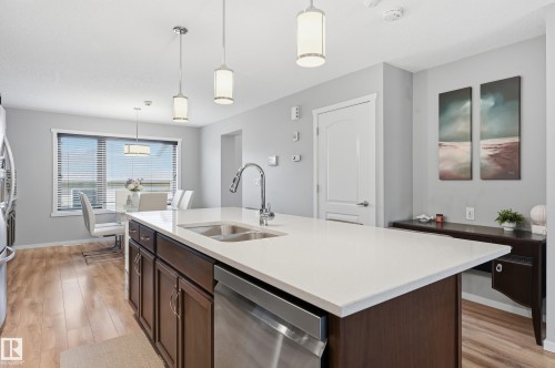 Kitchen island featuring a white countertop, undermount sink with a gooseneck faucet, and integrated dishwasher - 3457 Cutler Crescent, Edmonton, AB - Indoor Photo Showing Kitchen With Double Sink