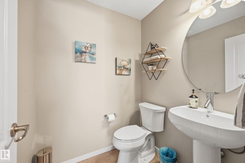 Pedestal sink with chrome faucet, circular mirror, and overhead vanity lighting - 3457 Cutler Crescent, Edmonton, AB - Indoor Photo Showing Bathroom