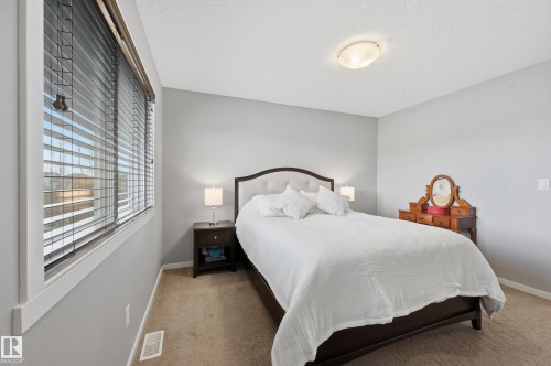 Carpeted bedroom featuring neutral-toned walls, a large window with horizontal blinds, and a flush-mount ceiling light fixture - 3457 Cutler Crescent, Edmonton, AB - Indoor Photo Showing Bedroom