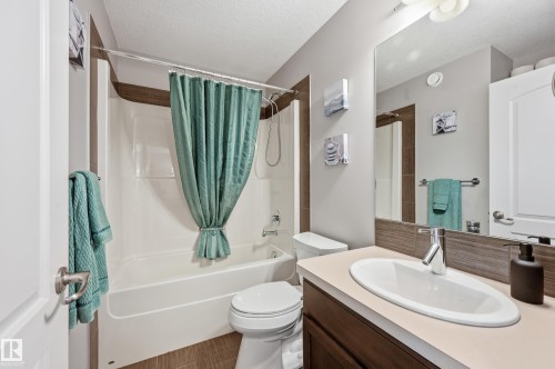 Full bathroom featuring a single vanity with a white oval sink, chrome faucet, and a large mirror - 3457 Cutler Crescent, Edmonton, AB - Indoor Photo Showing Bathroom