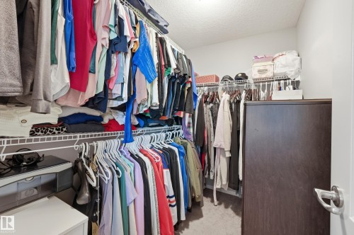 Walk-in closet featuring wire shelving, multiple hanging rods, and an integrated dark wood-finish cabinet - 3457 Cutler Crescent, Edmonton, AB - Indoor With Storage