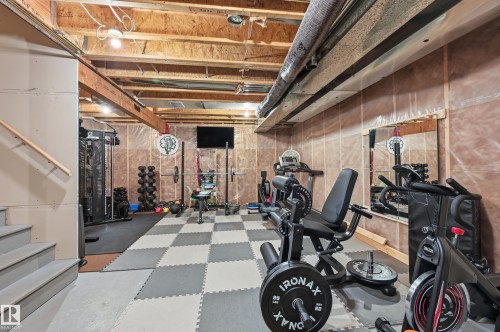 Basement space featuring exposed wood joists and structural beams, durable checkered floor mats, and a wall-mounted mirror - 3457 Cutler Crescent, Edmonton, AB - Indoor Photo Showing Basement