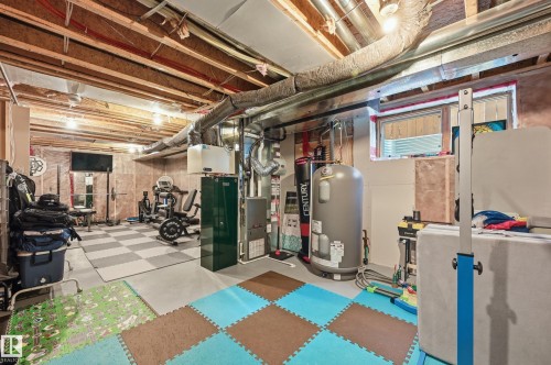 Unfinished basement featuring exposed ceiling joists and ductwork, a water heater, furnace, and a window providing natural light - 3457 Cutler Crescent, Edmonton, AB - Indoor Photo Showing Basement