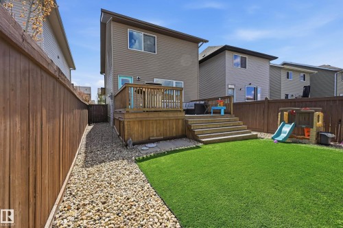 Fenced backyard featuring a raised wooden deck with stairs to a manicured artificial turf lawn - 3457 Cutler Crescent, Edmonton, AB - Outdoor With Deck Patio Veranda With Exterior