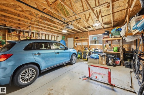 Spacious garage featuring exposed wood trusses, finished plywood walls, concrete flooring, and a window for natural light - 3457 Cutler Crescent, Edmonton, AB - Indoor Photo Showing Garage