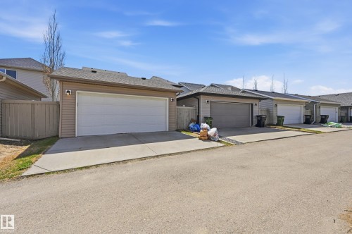 Attached single-car garage featuring a white overhead door and an exterior light fixture - 3457 Cutler Crescent, Edmonton, AB - Outdoor