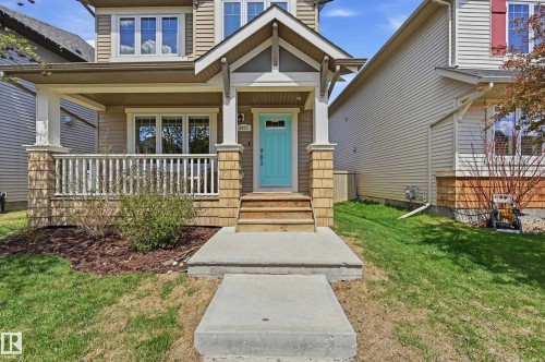 Inviting front facade featuring a covered porch with a white railing system, two-story construction, light-toned siding, and a vibrant turquoise entry door - 3457 Cutler Crescent, Edmonton, AB - Outdoor With Deck Patio Veranda With Facade