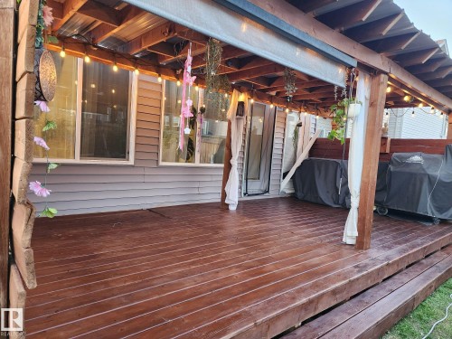 Spacious outdoor deck featuring rich wood-finish flooring, a covered pergola structure, and ambient string lighting - 22931 96 Avenue, Edmonton, AB - Indoor Photo Showing Basement