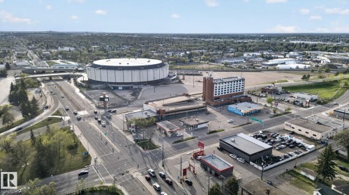 Urban landscape featuring a large, circular arena with a white roof and dark siding, surrounded by roadways and commercial properties - 11614 70 Street, Edmonton, AB 
