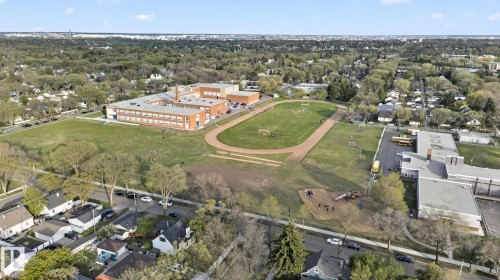Aerial perspective showcasing a sprawling educational campus with multiple buildings, athletic fields, and a running track - 11614 70 Street, Edmonton, AB 