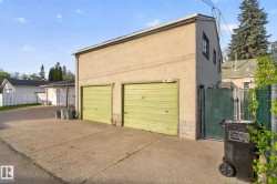 Detached two-story garage with two roll-up doors, stucco exterior, and a concrete driveway - 