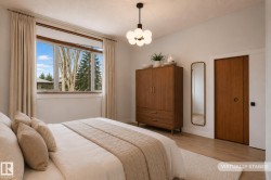 Bedroom featuring a prominent window, ceiling-mounted light fixture, wood-finish flooring, and a flush-mounted door - 