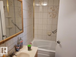 Bathroom featuring a built-in bathtub, a combination shower/tub fixture, and grab bars - 