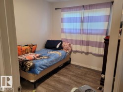Room featuring wood-finish flooring, light-toned walls, and a window with horizontal striped coverings - 