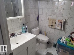 White tiled walls and flooring with a built-in vanity and integrated sink - 